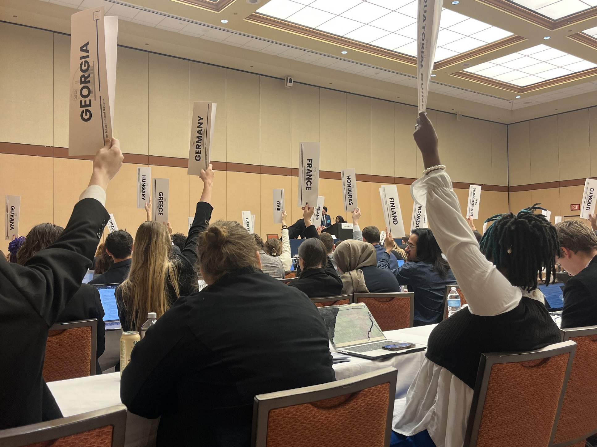 Representative Emily Bisset of Germany leads in raising their placard with a majority of surrounding votes to get Resolution 2-1 officially passed.